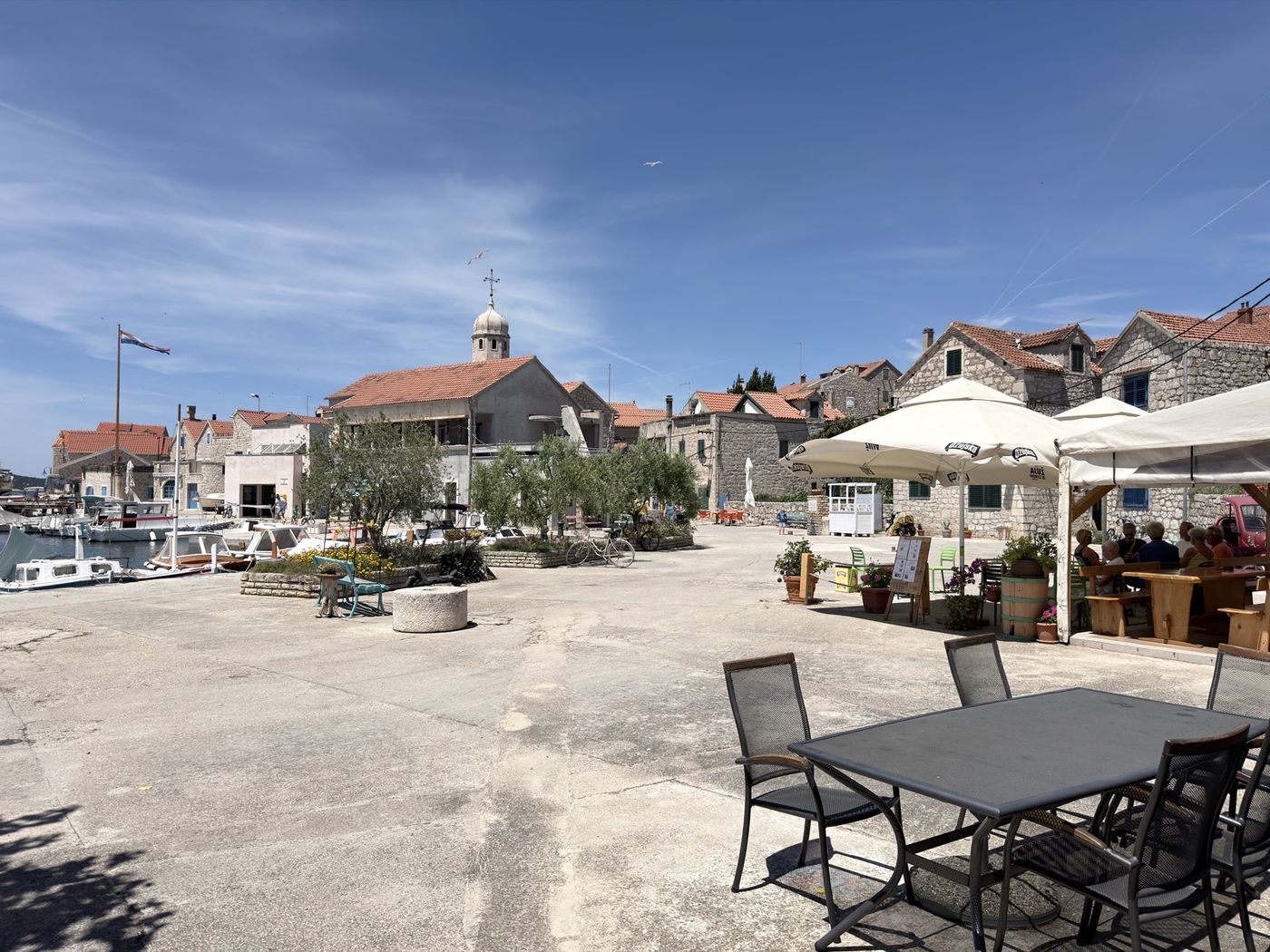 Kameni trg Prvić Šepurina s crkvom, maslinom i terasom konobe Bare